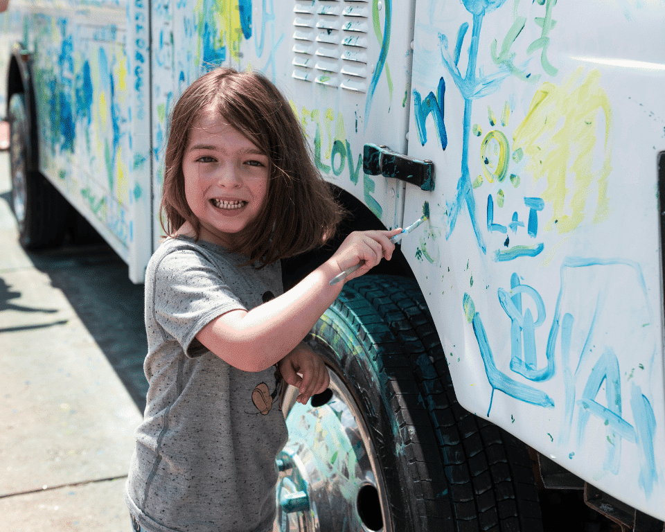 A girl paints on a truck at KidsFest at AthFest 2024.