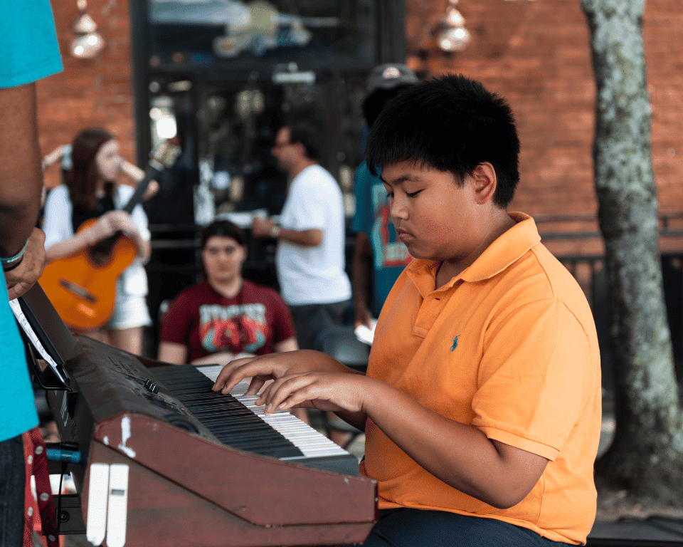 A boy plays the keyboard on the KidsFest at AthFest 2024 stage.